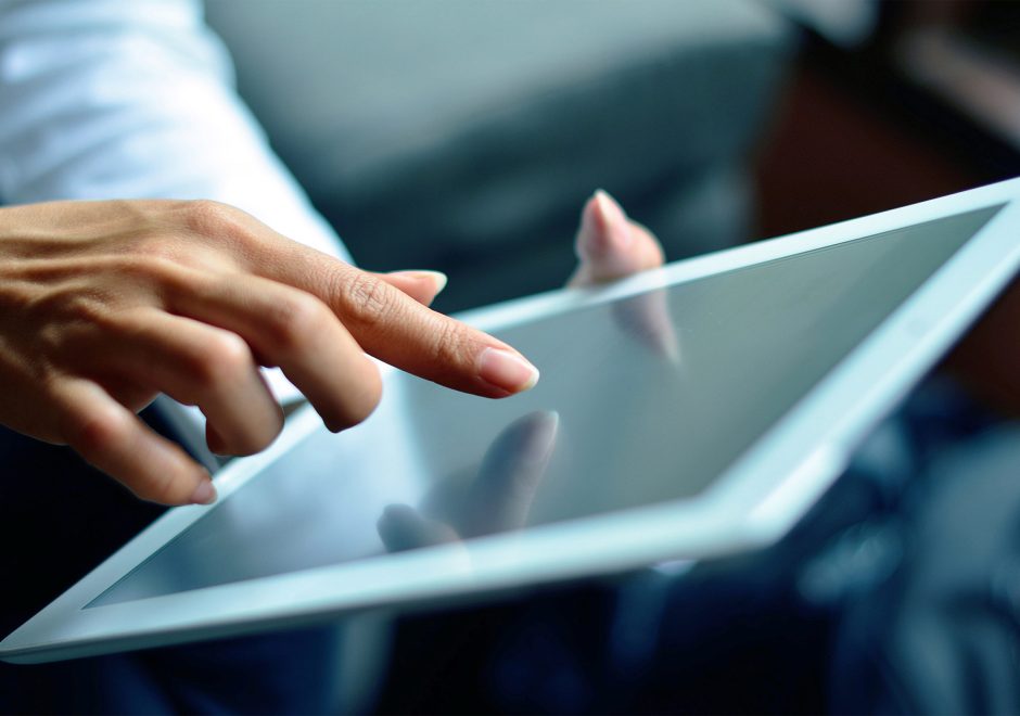 Businesswoman reading news article on her digital tablet on Fund HQ's news page